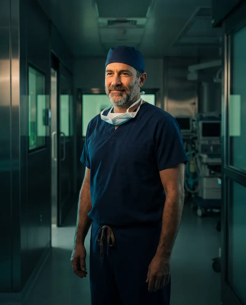 A surgeon in scrubs standing in an operating theater corridor